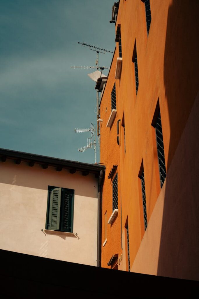 A view of urban buildings with TV antennas against a clear blue sky, showcasing architectural contrasts.