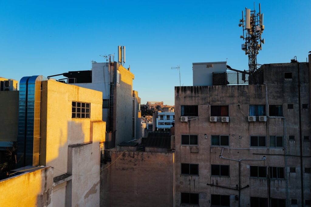 Urban skyline view showcasing rooftops and antennas during daytime with clear blue skies.